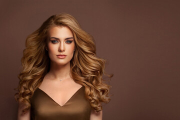 Perfect young model woman with long healthy wavy ginger hair on brown background. Beauty and haircare concept