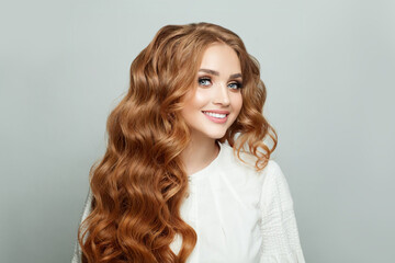 Happy cheerful woman with long ginger wavy hair against white background