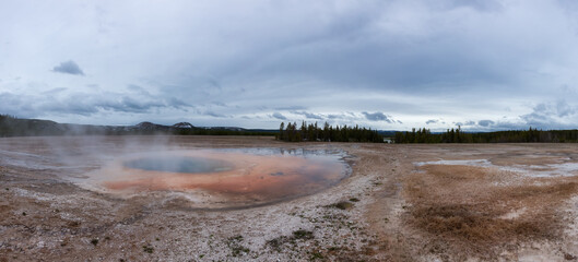 Hot spring Geyser with colorful water in American Landscape. Cloudy Sky. Yellowstone National Park, Wyoming, United States. Nature Background Panorama