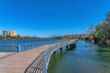 Boardwalk with concrete pavement and metal railings over Colorado River at Austin, Texas