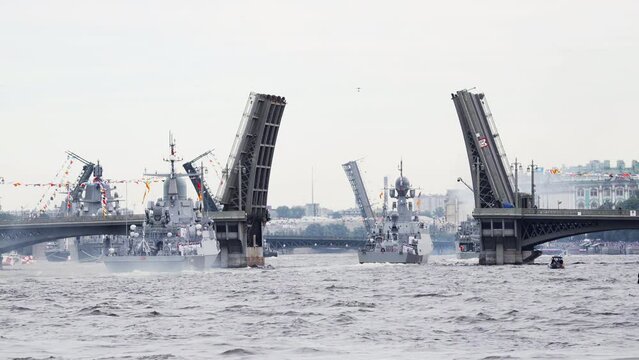 A lot of warships goes along the Neva River under open bridges at the time of the celebration of the day of Navy in cloudy weather, military motor boat