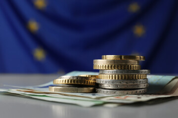 Coins and banknotes on table against European Union flag, closeup. Space for text