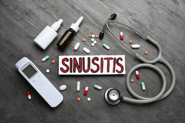 Card with word SINUSITIS, stethoscope, non-contact thermometer and different drugs on grey stone...