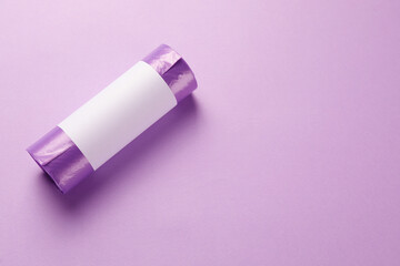 Roll of violet garbage bags on color background, top view. Space for text