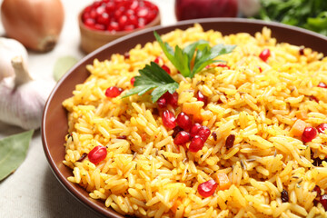 Tasty rice pilaf with pomegranate grains on table, closeup