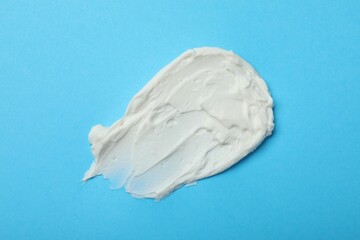 Smear of delicious cream cheese on light blue background, top view