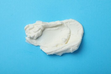 Smear of delicious cream cheese on light blue background, top view