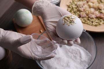 Woman in gloves making bath bomb at table, closeup