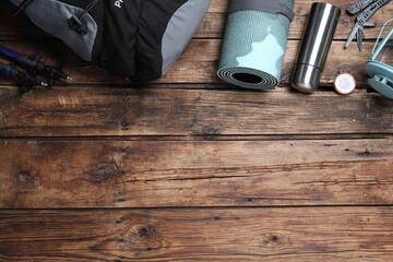 Flat lay composition with tourist backpack and other camping equipment on wooden background, space...