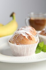 Tasty muffins served with mint on white table, closeup