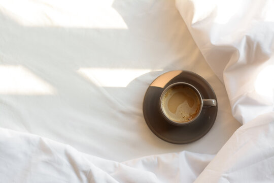 Aromatic morning coffee on bed, top view. Space for text