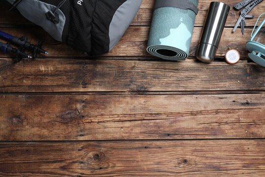 Flat lay composition with tourist backpack and other camping equipment on wooden background, space for text