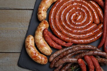 Different delicious sausages on wooden table, top view. Assortment of beer snacks