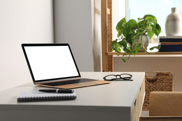 Workplace with modern laptop and glasses on white table. Mockup for design