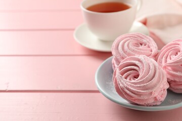 Delicious zephyrs served with tea on pink wooden table, space for text