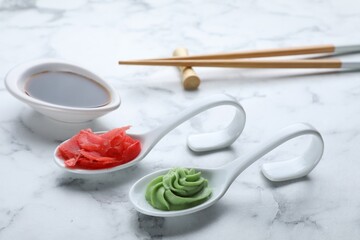 Swirl of wasabi paste, pickled ginger, soy sauce and chopsticks on white marble table