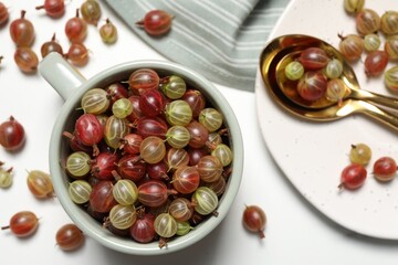 Fresh ripe gooseberries on white table, flat lay