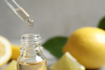 Citrus essential oil dripping from pipette into bottle, closeup. Space for text