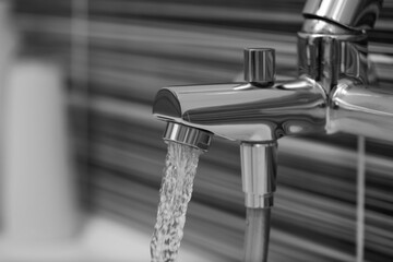 Water flowing from tap in bathroom, closeup