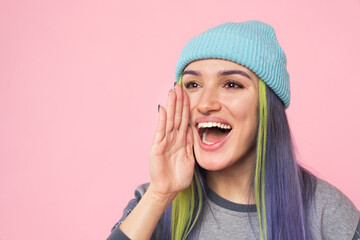 Smiling caucasian young woman teenage hipster girl using her palm as a loudspeaker telling secrets rumors news about sale offer discount isolated in pink background