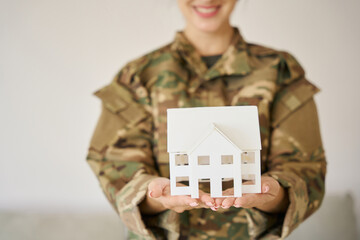 Toy homemade house in the hands of a female soldier - Powered by Adobe