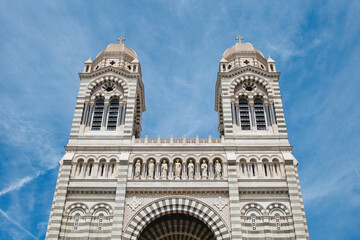 Fototapeta na wymiar Front view of the two towers of the Marseille Cathedral in front of a blue summer sky. Old, beautiful, romanesque-style cathedral in Marseille, France. Sightseeing in southern France. 