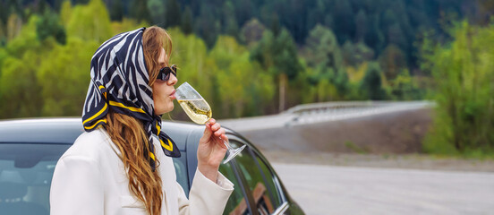 Woman with a glass of Wine on the Road next to the Car is waiting for a sober Driver. Designated driver service