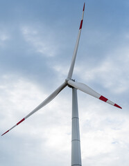 Blades on towers of wind turbines at sunset against cloudy sky. Close-up. Adyghe wind farm from many towers of wind turbines in field. Wind power complex of Rosatom.