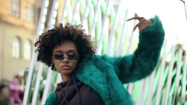 Young attractive woman with curly hair dancing rnb outdoor, stylish clothes