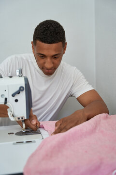 Smiling man enjoying making clothes in atelier