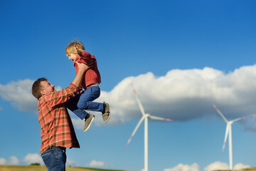 Eco activists man and child on background of power stations for renewable electric energy production. People and windmills. High wind turbines for generation electricity. Green energy