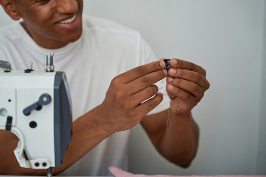 Smiling male tailor using sewing machine in atelier