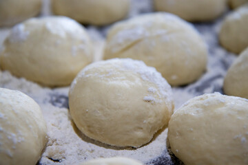 Fototapeta na wymiar selective focus on small and neat balls of air dough for baking sweet pies and buns. The concept of home cooking. Blurred background