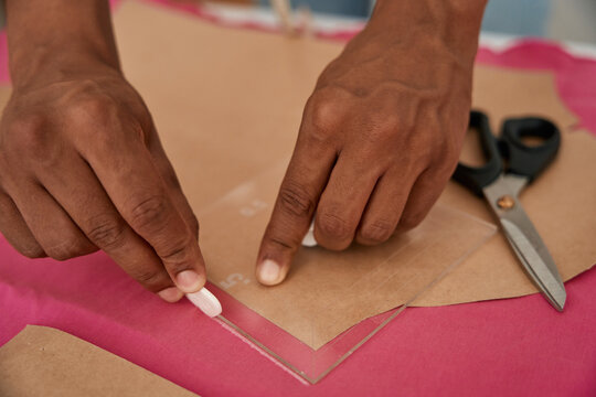 Male tailor making patterns on fabric before sewing
