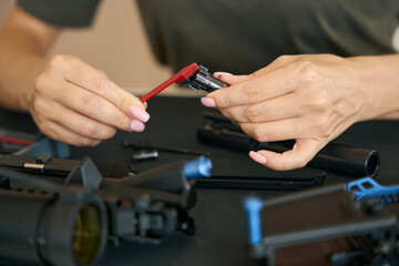 Military woman cleans part of machine gun with special brush