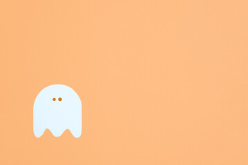 Minimalist halloween design, white cute ghost isolated on pastel orange color background, trendy composition with copy space.