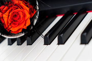 Unfading red rose box on keys of black piano. Piano keys on the background. Romantic concept. Selective focus, noisy and grainy effect.