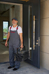 Portrait of adult builder in overalls and with tool box