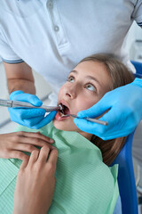 Stomatologist performing cavity preparation procedure in teenage patient
