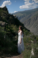 Naklejka na ściany i meble Bride in the mountains wedding image. A beautiful young woman in a wedding dress walks in the mountains.