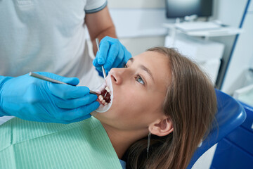 Stomatologist inspecting oral cavity of young patient