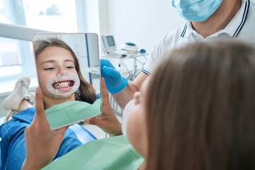 Teenage patient examining her teeth after dental procedure