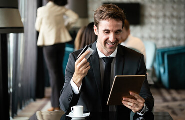 Portrait of cheerful businessman paying for order with credit card in cafe