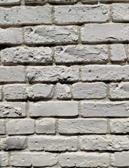 A fragment of an old brick wall painted with white paint.