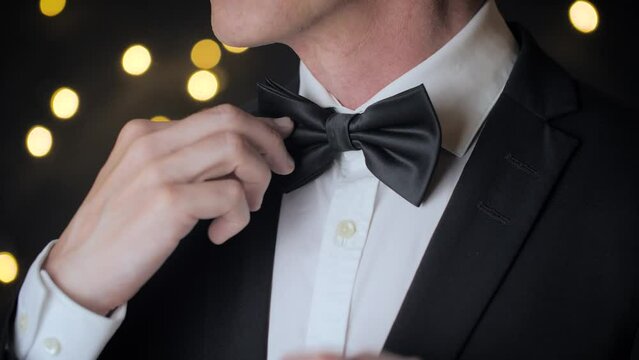 Close up view of man adjusts his bow tie.