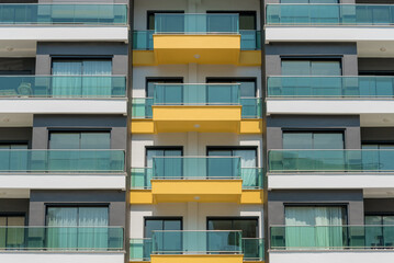 The front of a modern apartment building with glass balconies.
