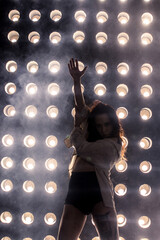 Sexy girl dance on front of spot light wall with smoke