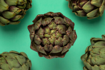 Fototapeta premium Big fresh artichokes on green background. Top view.