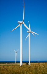 Windmill for electric power production against blue sky.