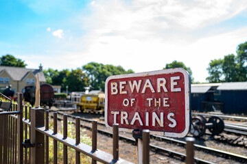 Shallow focus of an old, wrought iron beware of the Trains sign seen located at a steam-era railway...